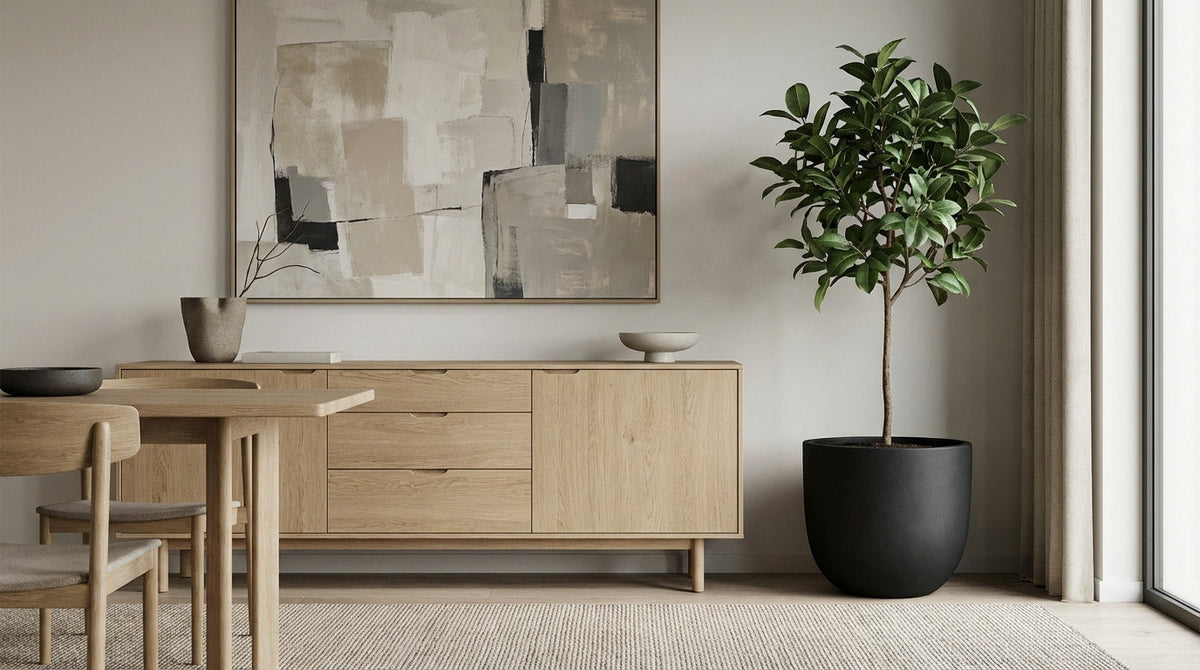 Schwarzer runder Pflanzkübel mit Zimmerbaum neben hellem Holz-Sideboard im modernen Esszimmer