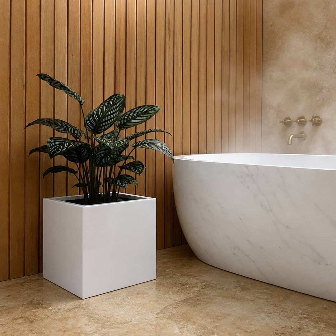 Quadratischer Pflanzkübel in Hochglanz-Weiß mit Calathea neben freistehender Marmorbadewanne vor Holzlamellenwand