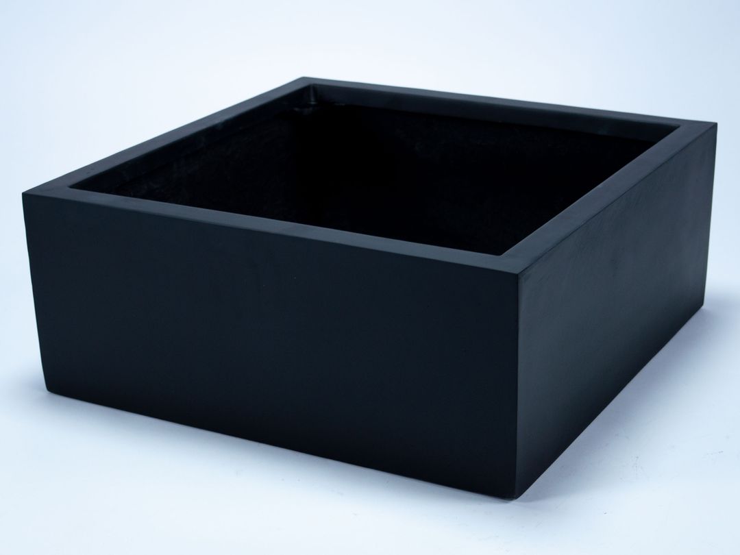 Niedriger quadratischer Pflanzkübel aus Fiberglas in Schwarz-matt, leer und schräg von oben vor hellem Hintergrund