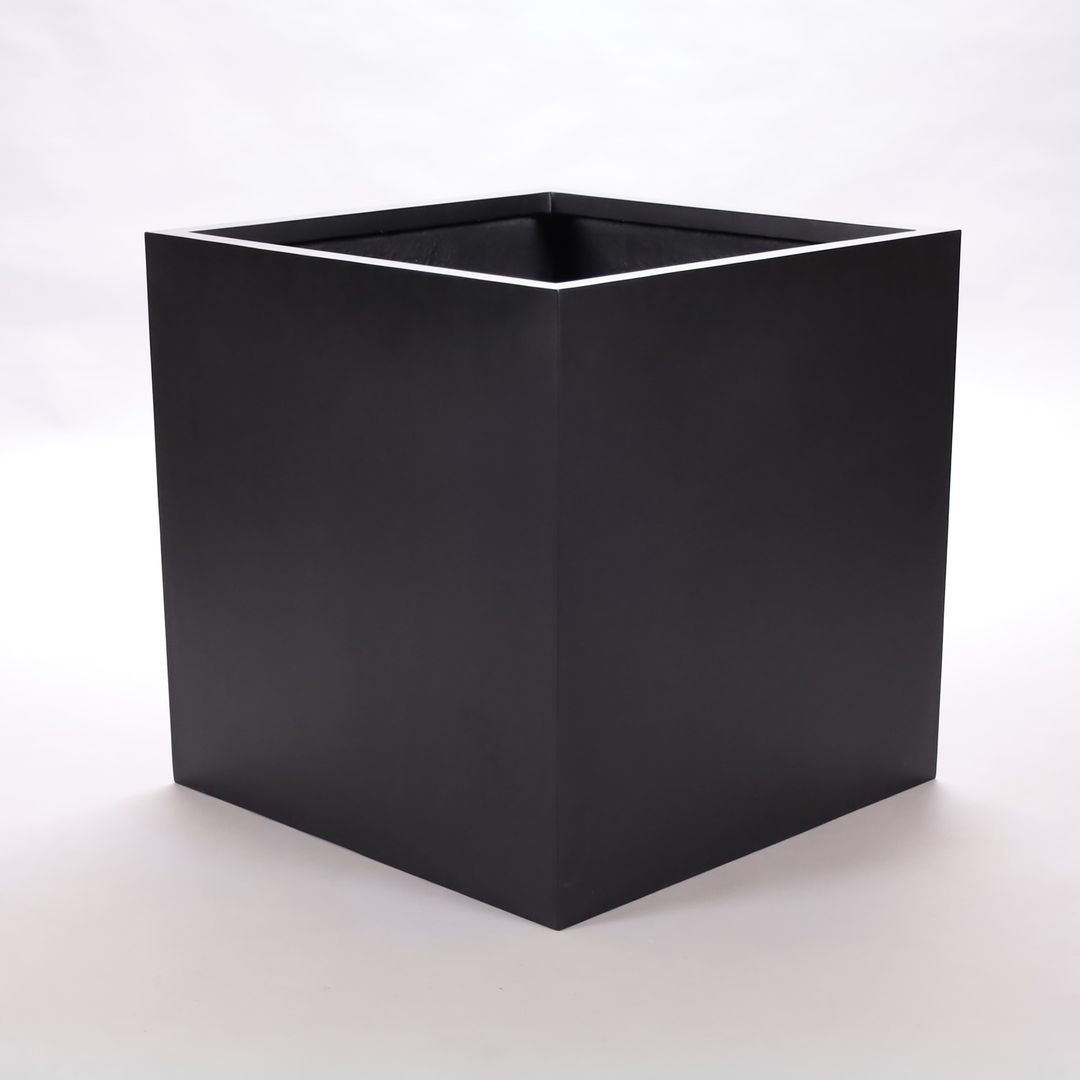 Leerer quadratischer Pflanzkübel aus Fiberglas in Schwarz-matt in Würfelform vor hellem Studiohintergrund