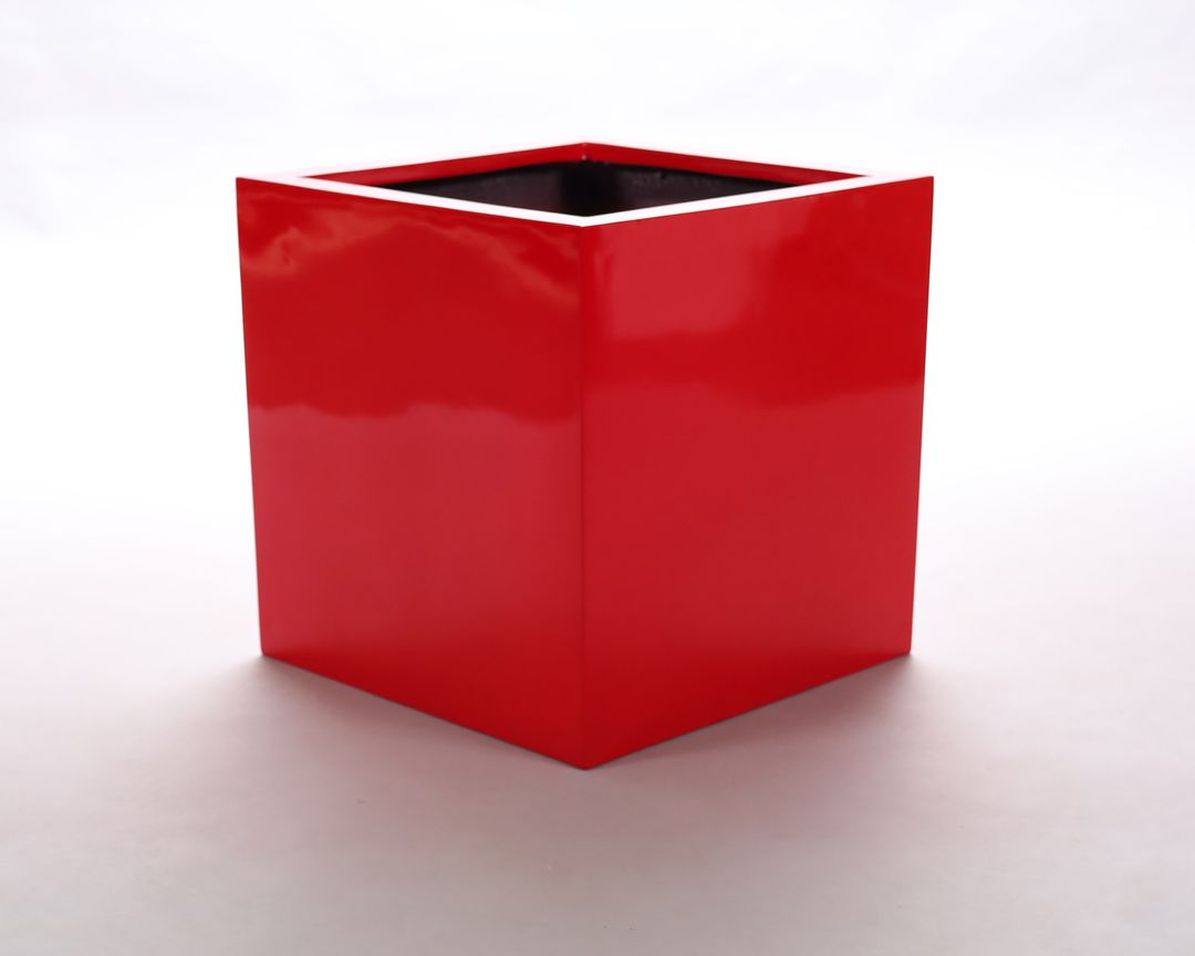 Quadratischer Pflanzkübel aus Fiberglas in glänzendem Hochglanz Rot vor hellem Hintergrund, schräg von oben gesehen