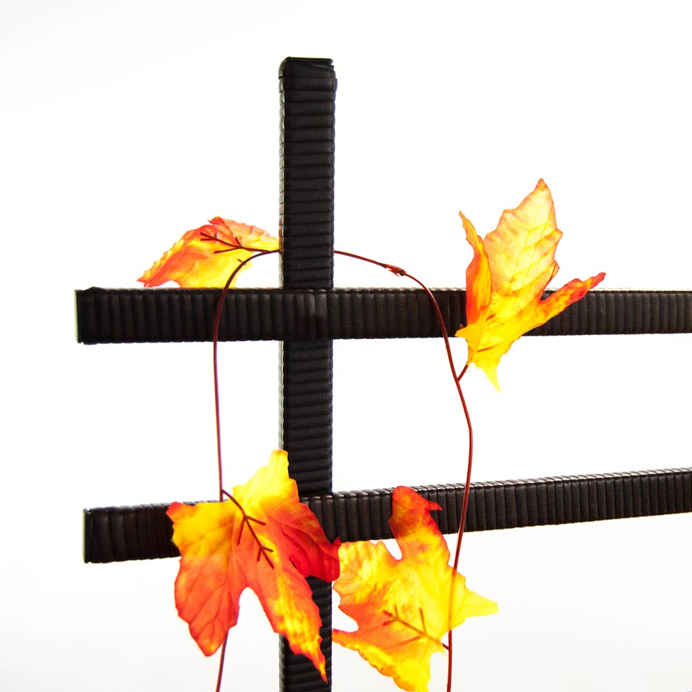 Detail des Rankgitters aus Polyrattan in Coffee Braun mit gekreuzten Streben und rankenden orangegelben Herbstblättern