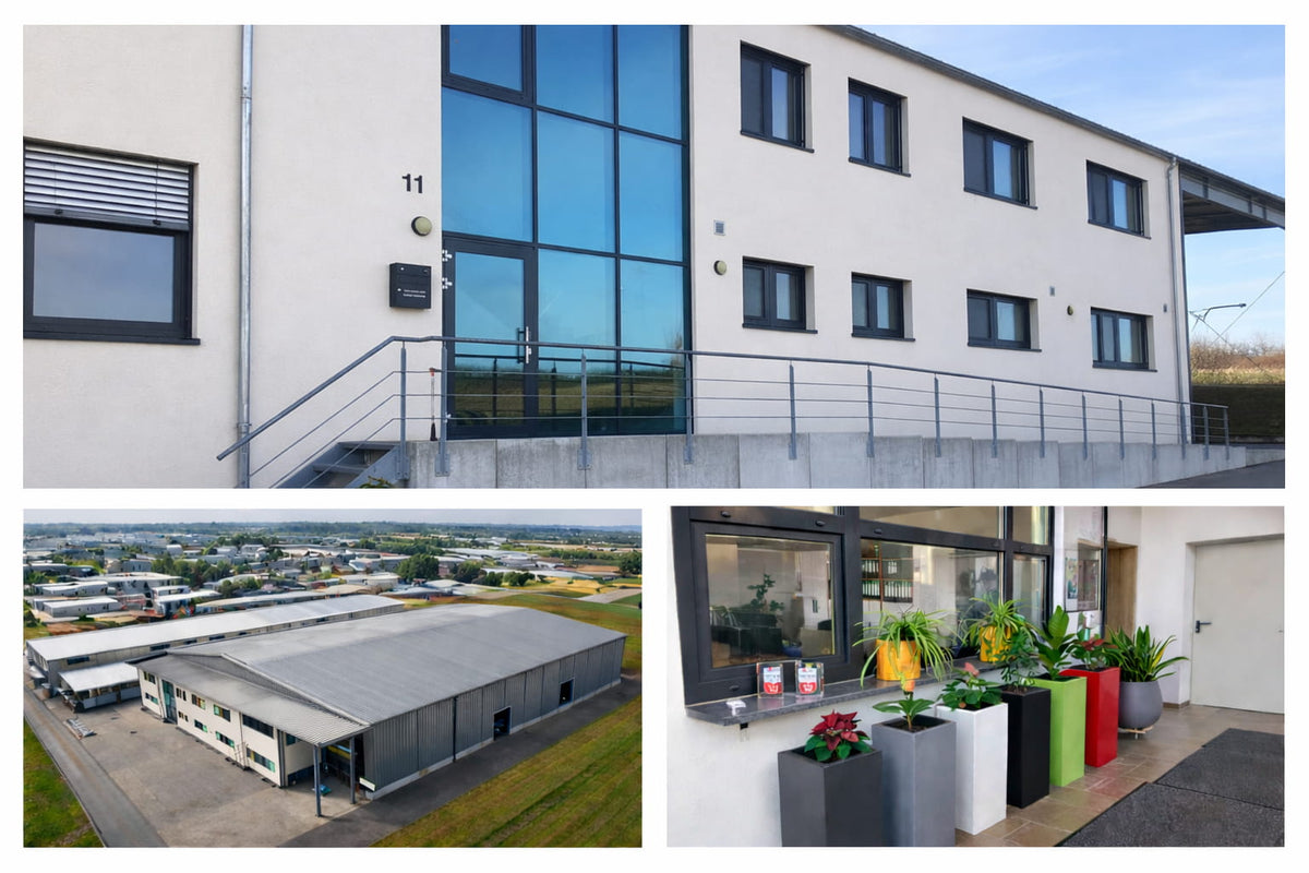 Firmensitz der Tran Company GmbH – modernes Bürogebäude, Lagerhalle im Gewerbegebiet und Eingangsbereich mit dekorativen Pflanzgefäßen in verschiedenen Farben