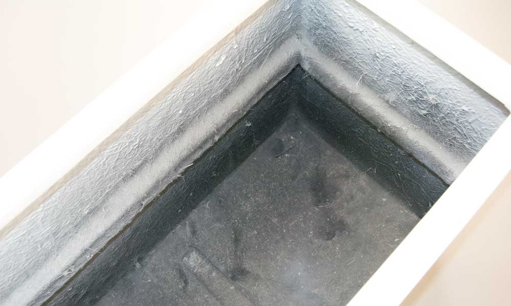 Blick in das Innere eines rechteckigen Pflanzkübels in Hochglanz Weiß mit grauer, rauer Innenseite und Boden