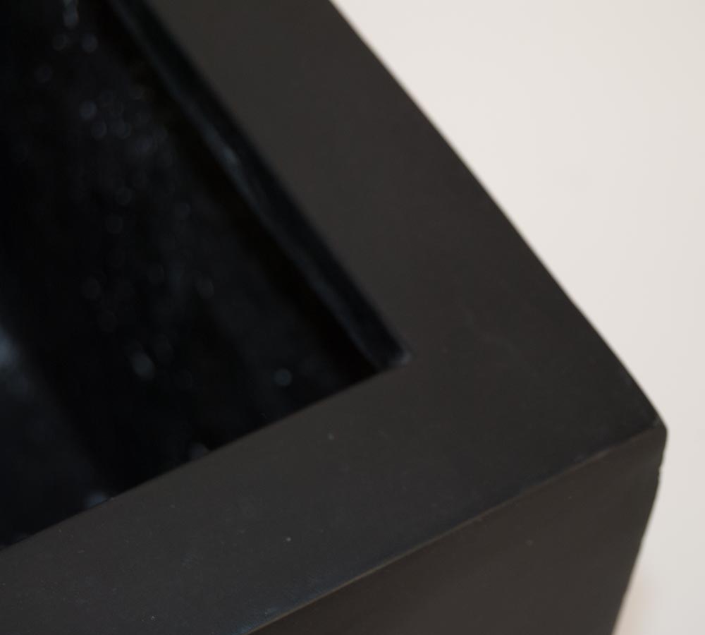 Nahaufnahme der Ecke eines schwarz-matten eckigen Pflanzkübels aus Fiberglas mit Blick auf Rand und Innenseite