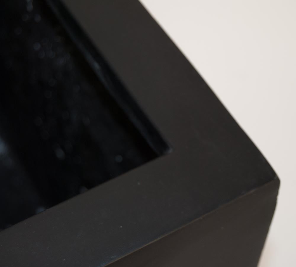 Nahaufnahme der Ecke eines schwarz-matten eckigen Pflanzkübels aus Fiberglas mit Blick auf Rand und Innenseite