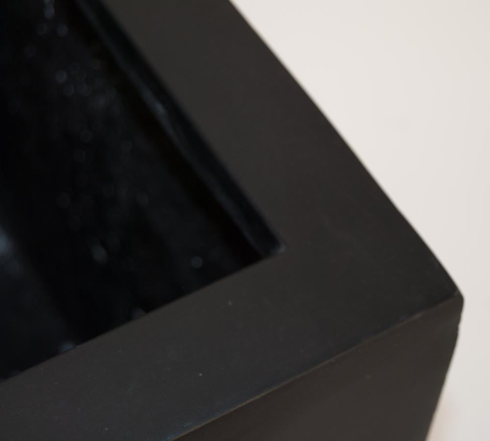 Nahaufnahme der Ecke eines schwarz-matten eckigen Pflanzkübels aus Fiberglas mit Blick auf Rand und Innenseite