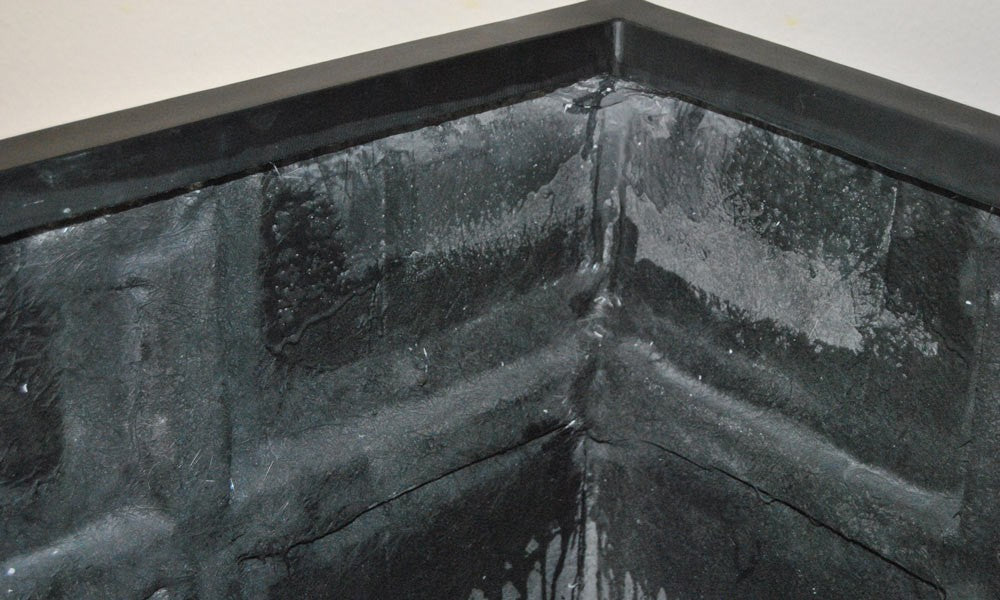 Detailansicht der Innenecke eines quadratischen Pflanzkübels aus Fiberglas in Schwarz-matt mit Rand und rauer Innenwand