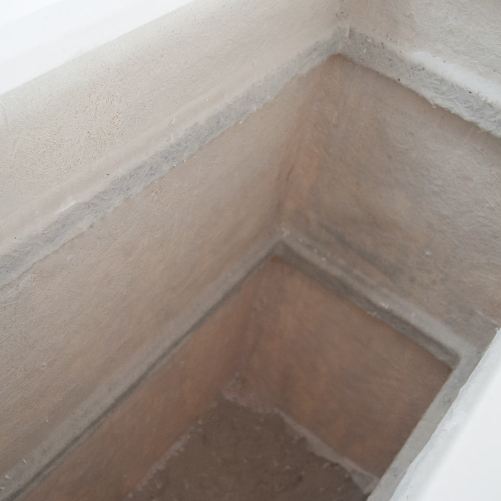 Blick in das Innere eines rechteckigen Pflanzkübels aus Fiberglas mit sichtbarer Faserstruktur an Wänden und Boden