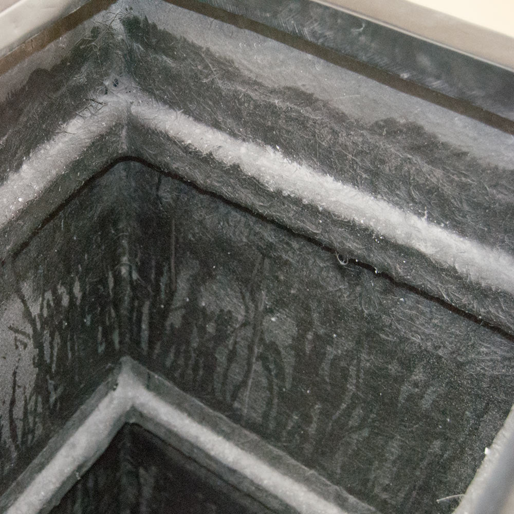 Blick in die Innenecke eines schwarzen rechteckigen Pflanzkübels aus Fiberglas mit sichtbarer Faserstruktur
