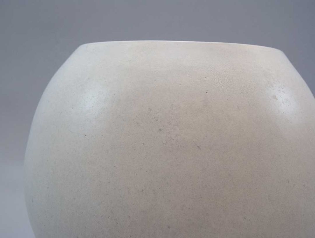 Nahaufnahme des oberen Teils eines kugelförmigen Pflanzkübels aus Fiberglas in Perlmuttweiß mit fein gesprenkelter Oberfläche