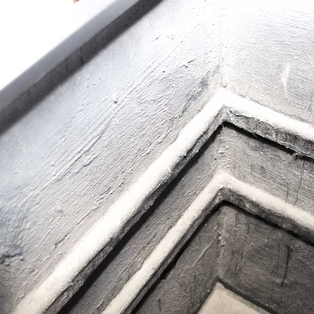 Nahaufnahme einer Ecke des rechteckigen Pflanzkübels aus Fiberglas mit rauer grauer Oberfläche und abgestuften Kanten