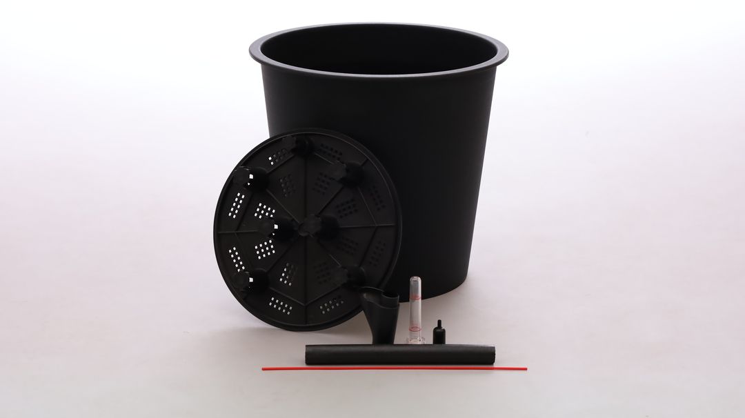 Schwarzer runder Pflanzeinsatz mit gelochter Bodenplatte, Einfüllrohr und Wasserstandsanzeiger vor hellem Hintergrund