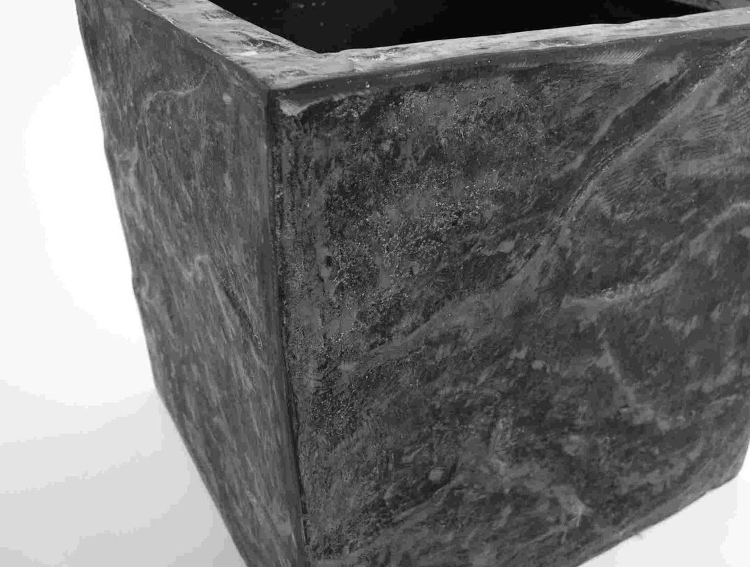 Nahaufnahme der Ecke eines quadratischen Pflanzkübels in Stein-Optik anthrazit grau mit heller Marmorierung