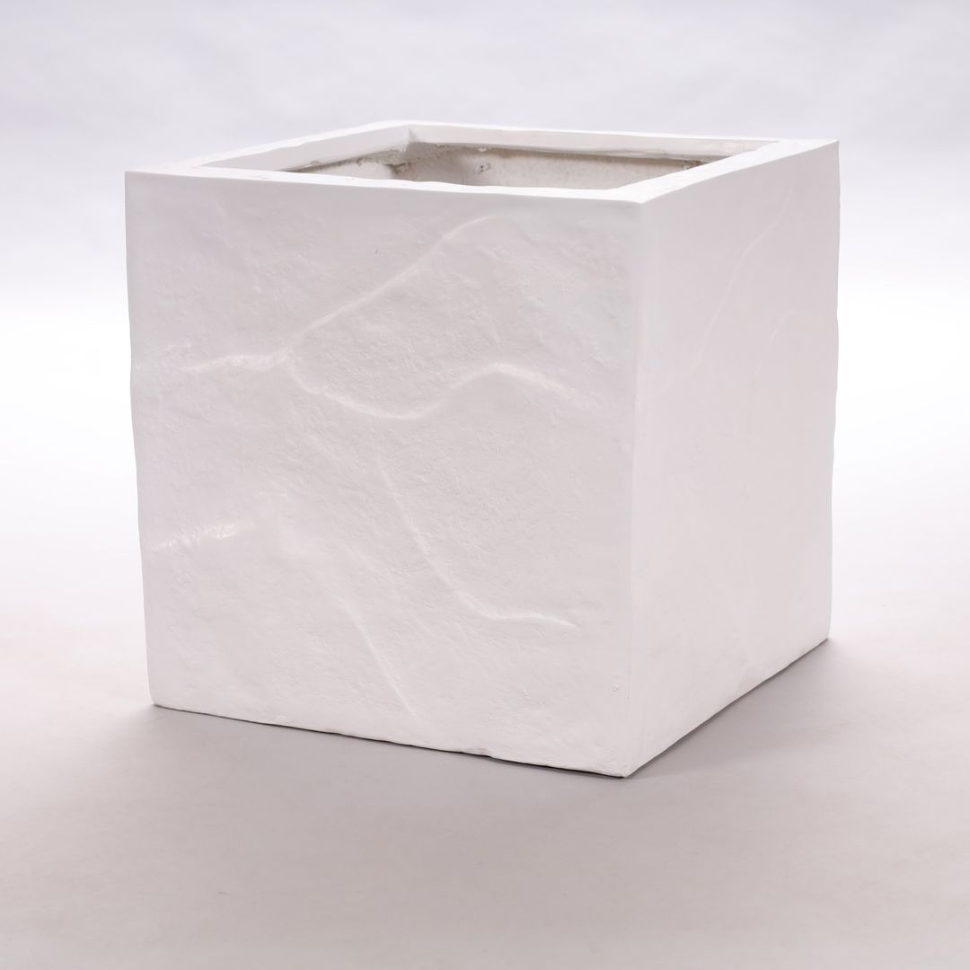 Quadratischer Pflanzkübel aus Fiberglas in Stein-Optik in Weiß mit reliefartiger Oberfläche vor hellgrauem Hintergrund