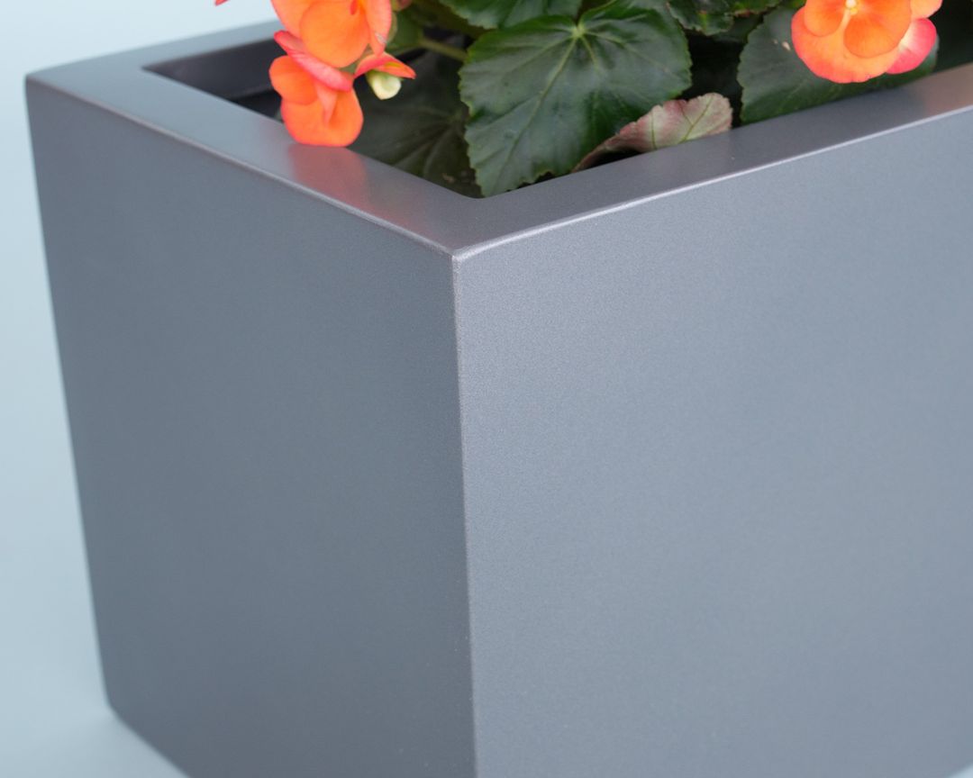 Detailansicht der Ecke eines anthrazit-metallic Pflanzkübels aus Fiberglas mit orange blühender Begonie