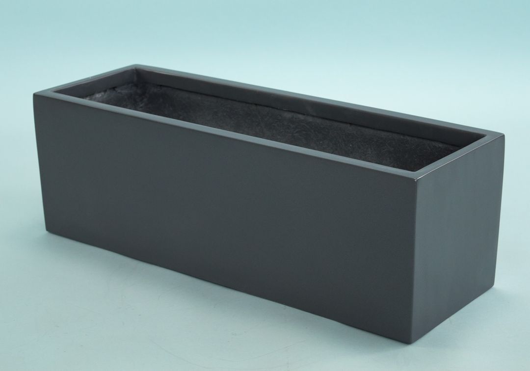 Rechteckiger Pflanzkübel aus Fiberglas in Anthrazit-Metallic, leer und schräg von oben vor hellblauem Hintergrund