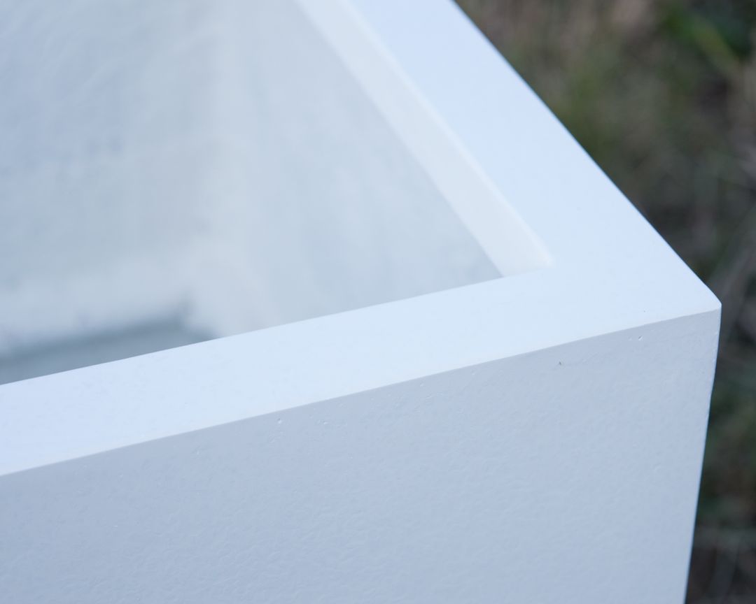 Nahaufnahme der Ecke eines rechteckigen Pflanzkübels aus Fiberglas in Perlmuttweiß mit abgesetztem oberem Rand