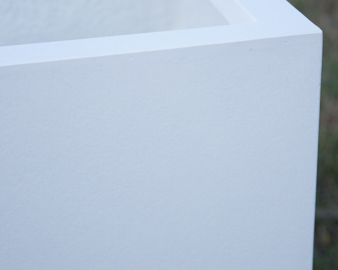 Nahaufnahme der Ecke eines perlmuttweißen Pflanzkübels aus Fiberglas mit feiner Oberflächenstruktur und Rand
