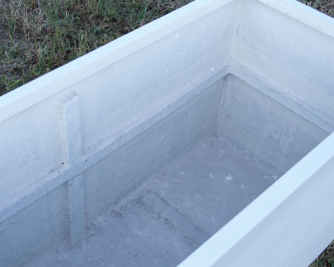 Blick ins Innere eines rechteckigen Pflanzkübels aus Fiberglas in Perlmuttweiß mit Verstärkungsrippe, auf Rasen