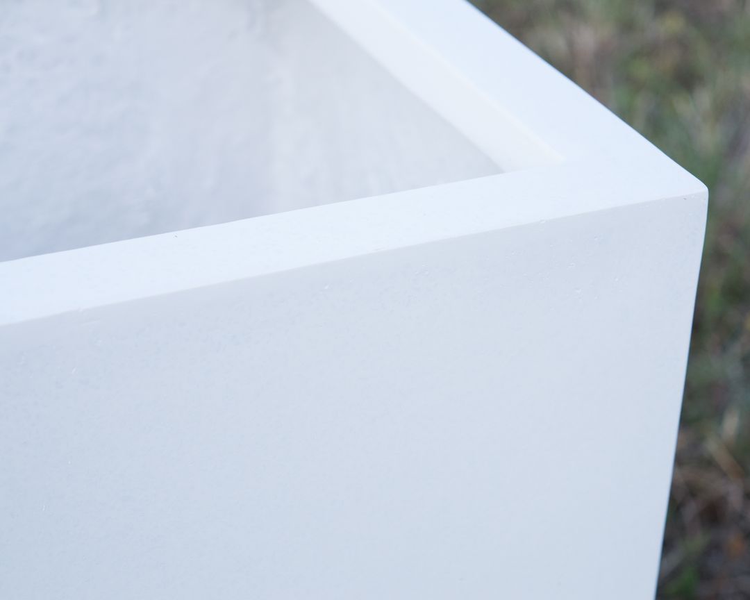 Nahaufnahme der Ecke eines perlmuttweißen Pflanzkübels aus Fiberglas mit abgesetztem Rand und matter Oberfläche