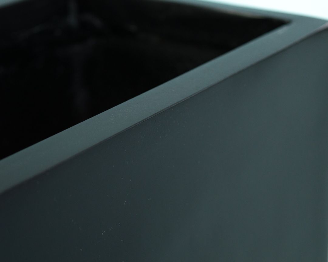 Nahaufnahme der Ecke und des oberen Randes eines rechteckigen Pflanzkübels aus Fiberglas in Schwarz-matt