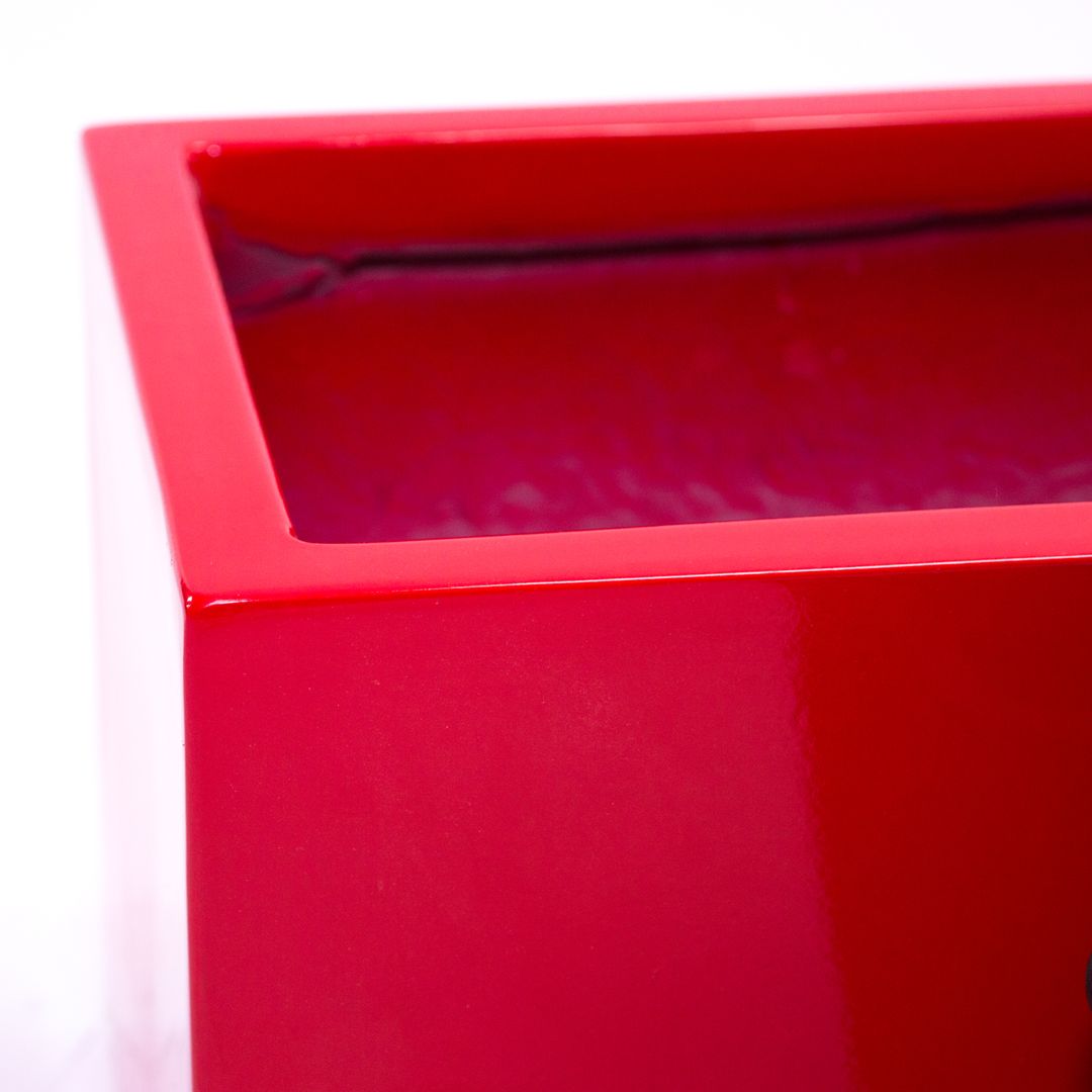 Nahaufnahme der Ecke eines rechteckigen Pflanzkübels aus Fiberglas in Hochglanz Rot mit glänzendem Rand und Innenraum