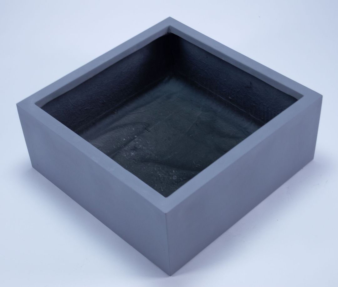 Niedriger quadratischer Pflanzkübel aus Fiberglas in Grau, schräg von oben mit Blick in den dunklen Innenraum