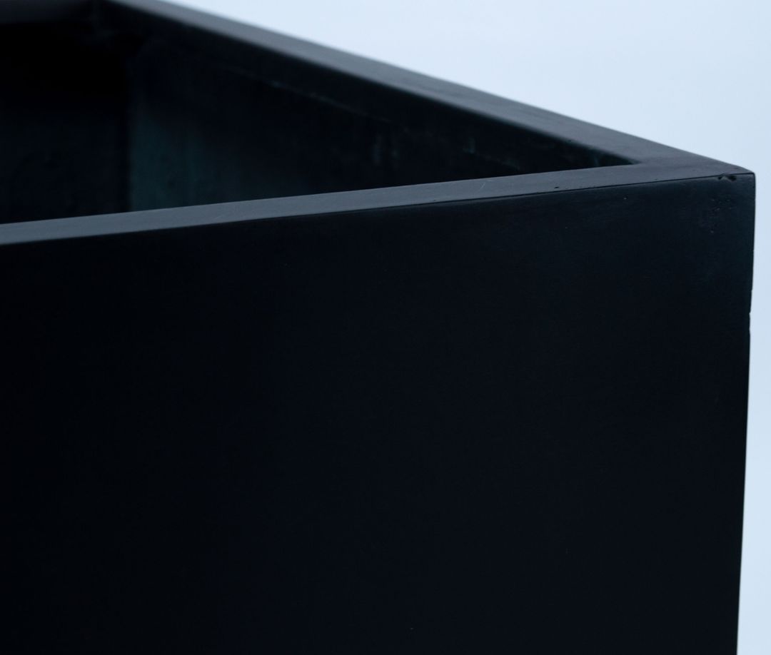 Nahaufnahme der oberen Ecke eines quadratischen Pflanzkübels aus Fiberglas in Schwarz-matt mit Blick auf den Rand