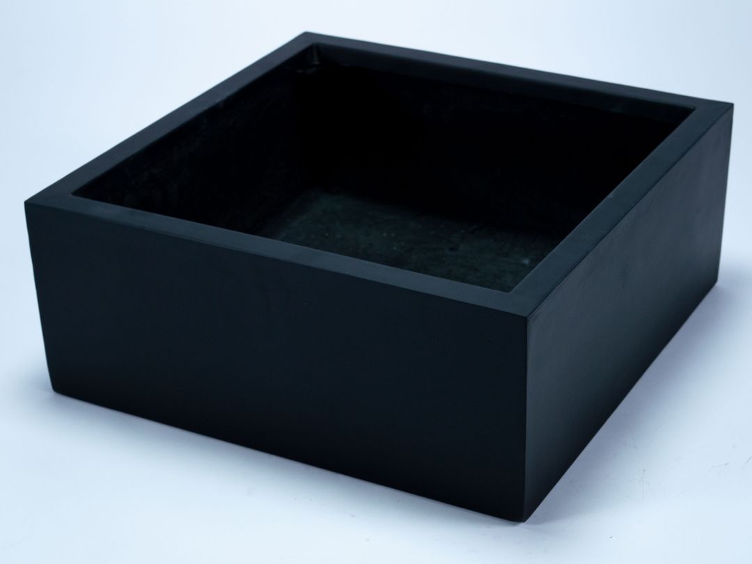 Niedriger quadratischer Pflanzkübel aus Fiberglas in Schwarz-matt, leer und schräg von oben vor hellem Hintergrund