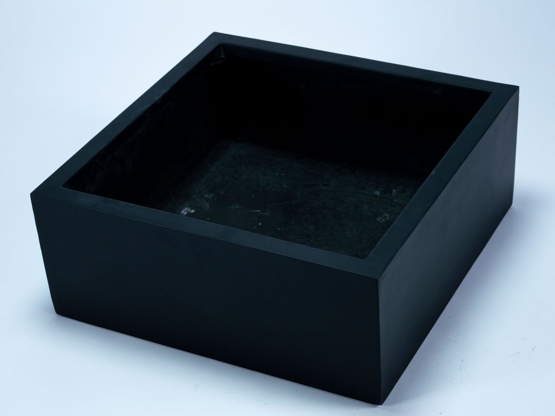 Niedriger quadratischer Pflanzkübel aus Fiberglas in Schwarz-matt, schräg von oben mit Blick in den Innenraum