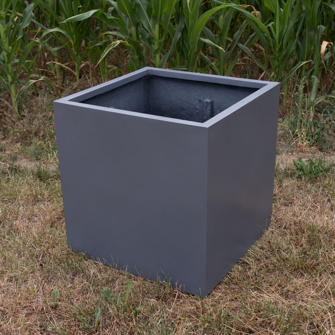 Quadratischer Pflanzkübel aus Fiberglas in Anthrazit metallic, leer auf trockener Wiese vor einem Maisfeld