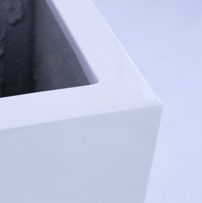 Quadratischer Pflanzkübel aus Fiberglas in Weiß ohne Bepflanzung auf einer gefliesten Treppenstufe vor heller Wand
