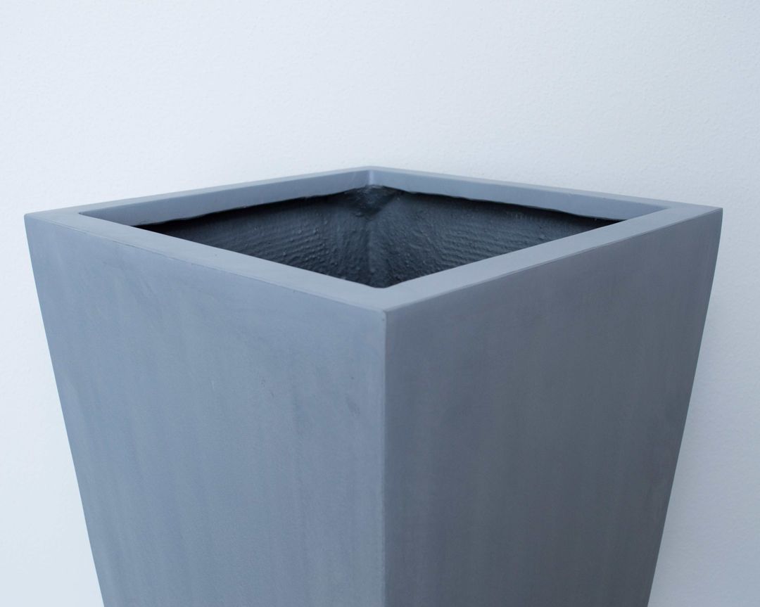 Oberer Rand eines grauen, konischen Pflanzkübels aus Fiberglas mit Blick in die quadratische Öffnung