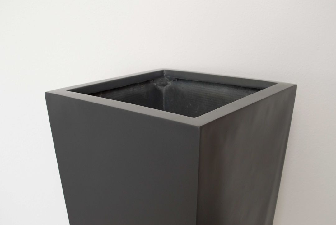 Oberer Rand und Öffnung eines konischen Pflanzkübels in Anthrazit metallic aus Fiberglas vor heller Wand