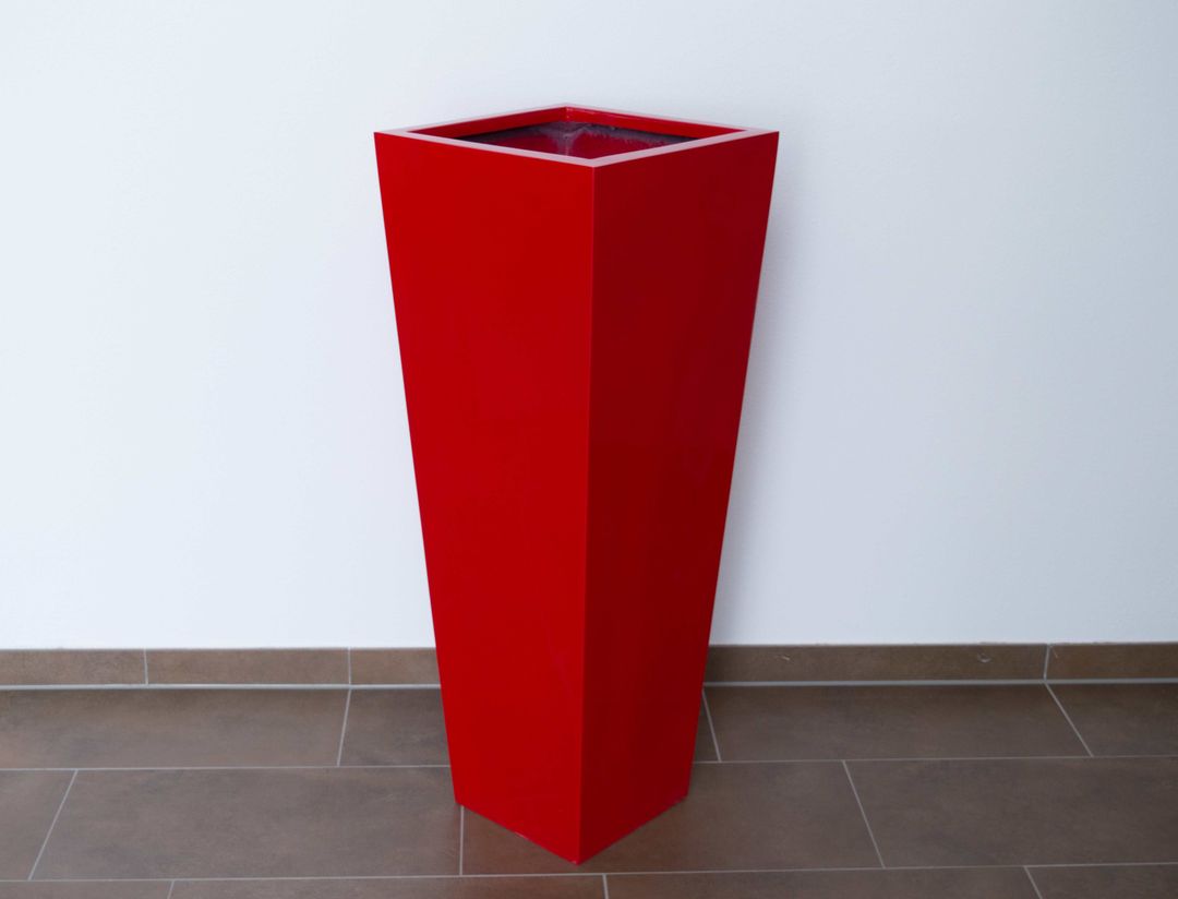 Konische Pflanzsäule aus Fiberglas in Hochglanz Rot auf braunem Fliesenboden vor weißer Wand