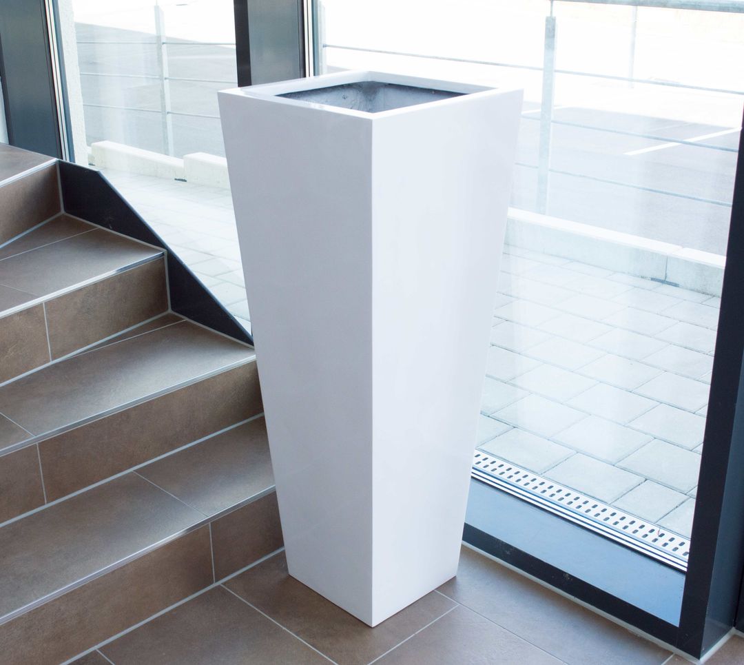 Hoher konischer Pflanzkübel in Hochglanz Weiß aus Fiberglas neben einer Treppe vor einer großen Glasfront
