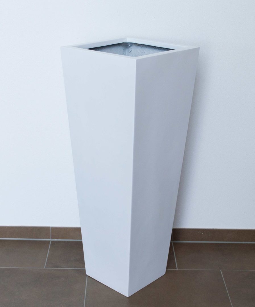 Weißer Pflanzkübel aus Fiberglas als hohe konische Säule vor weißer Wand auf braunem Fliesenboden
