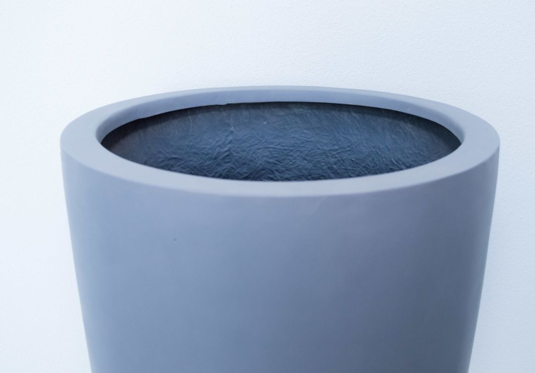 Oberer Rand eines grauen, runden konischen Pflanzkübels aus Fiberglas mit Blick in die dunkle Innenseite