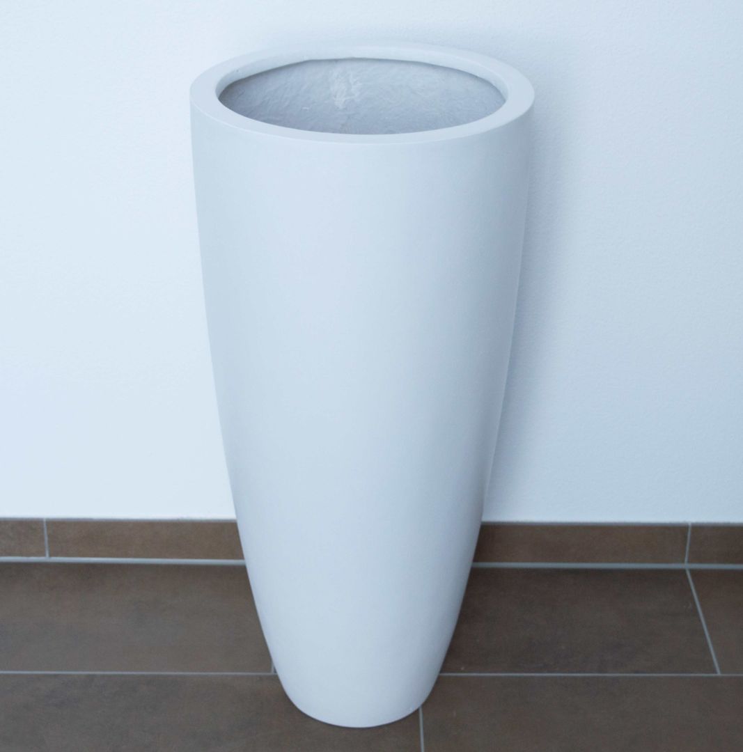 Hoher runder konischer Pflanzkübel aus Fiberglas in Perlmuttweiß, leer auf braunem Fliesenboden vor weißer Wand