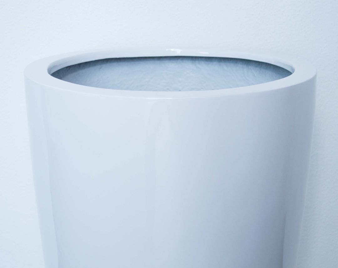 Oberer Rand eines runden konischen Pflanzkübels aus Fiberglas in Hochglanz weiß vor einer hellen Wand