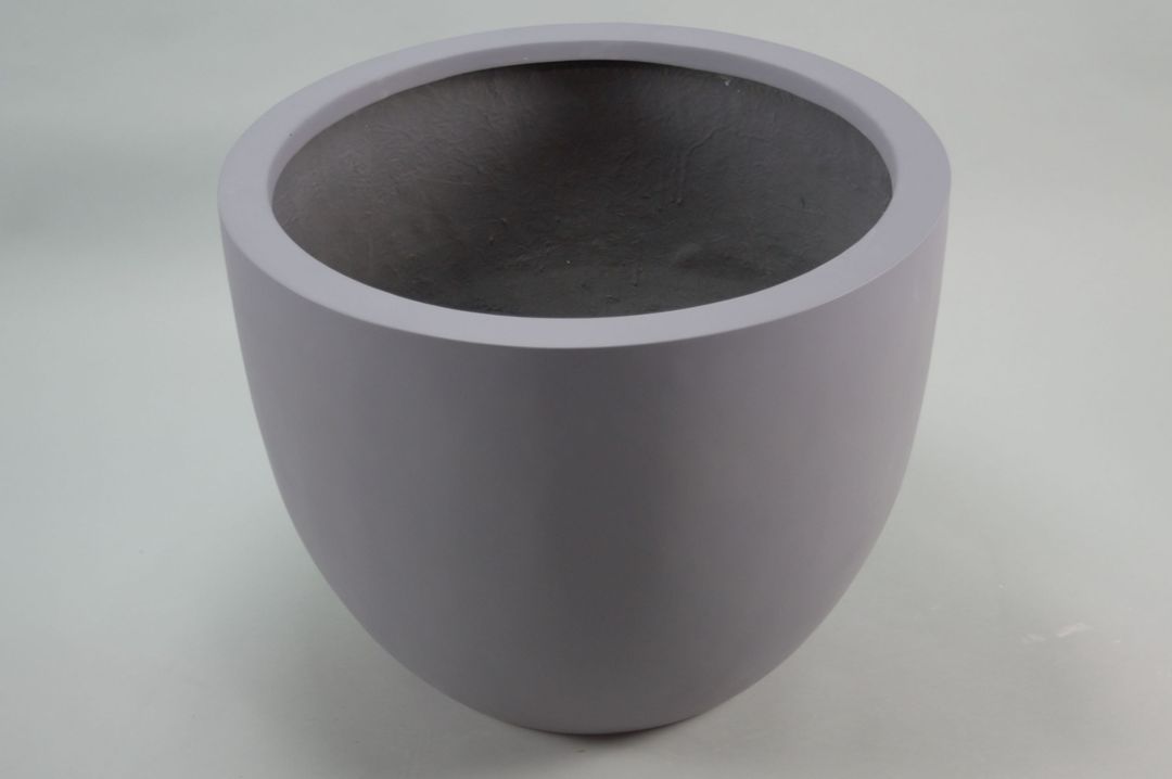 Runder grauer Pflanzkübel aus Fiberglas mit nach unten verjüngter Form, schräg von oben vor grauem Hintergrund