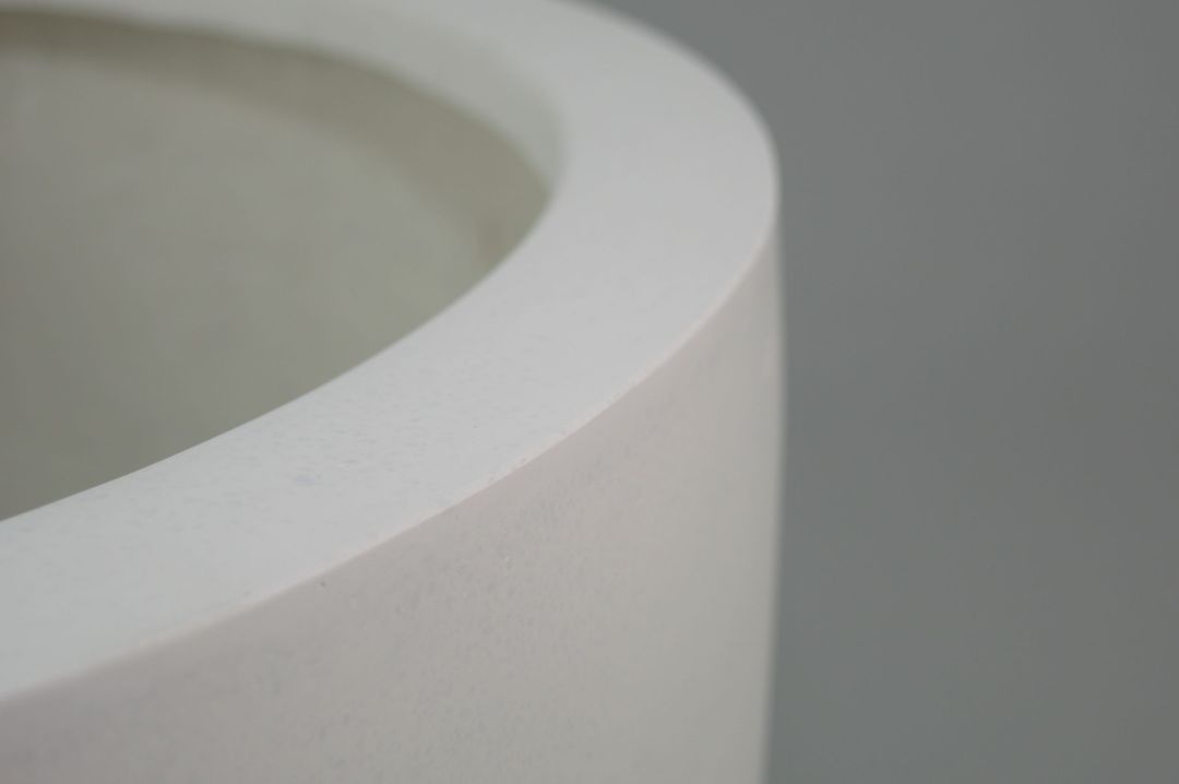 Nahaufnahme des runden Rands eines perlmuttweißen Pflanzkübels aus Fiberglas mit matter, fein strukturierter Oberfläche