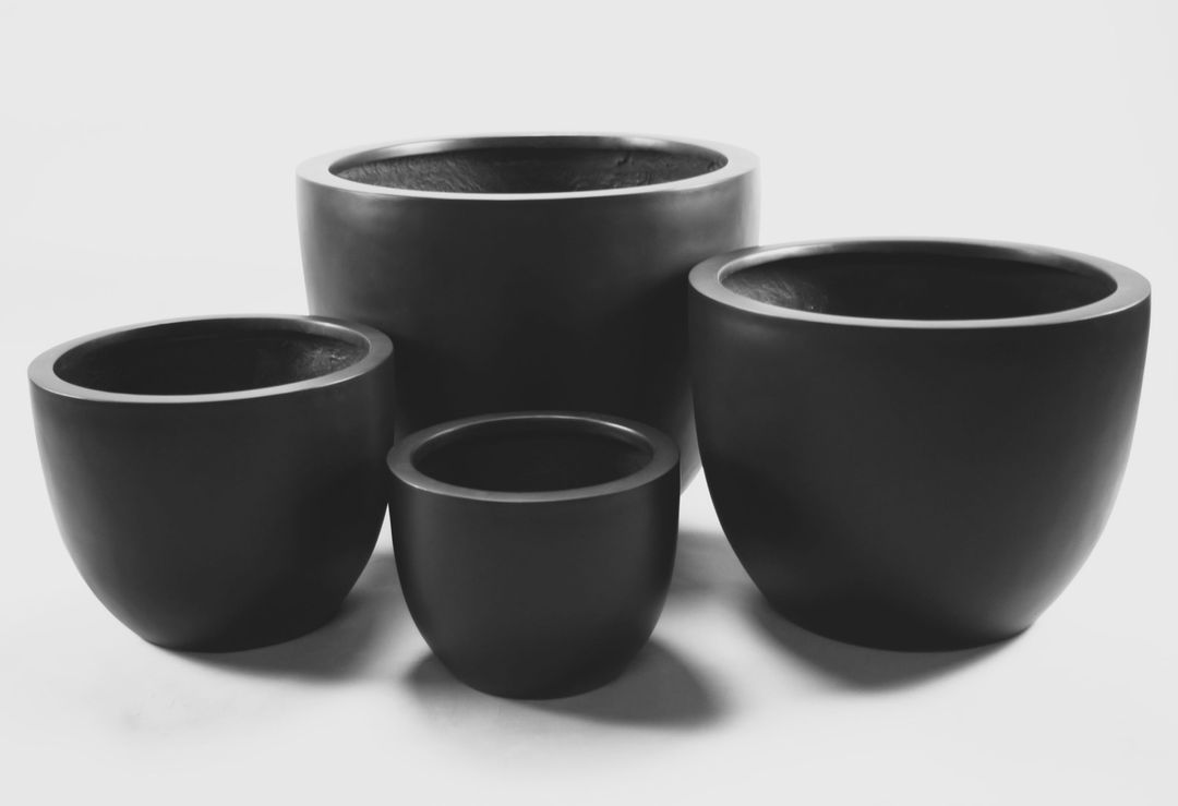 Vier schwarz-matte Pflanzkübel aus Fiberglas in rund konischer Form und unterschiedlichen Größen als Gruppe