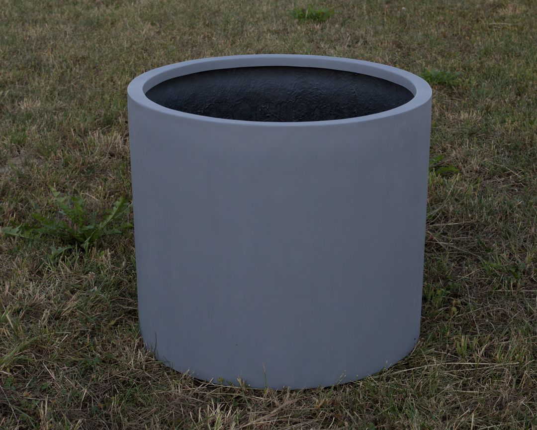 Zylindrischer Pflanzkübel aus Fiberglas in Grau ohne Bepflanzung auf einer Rasenfläche, schräg von oben gesehen