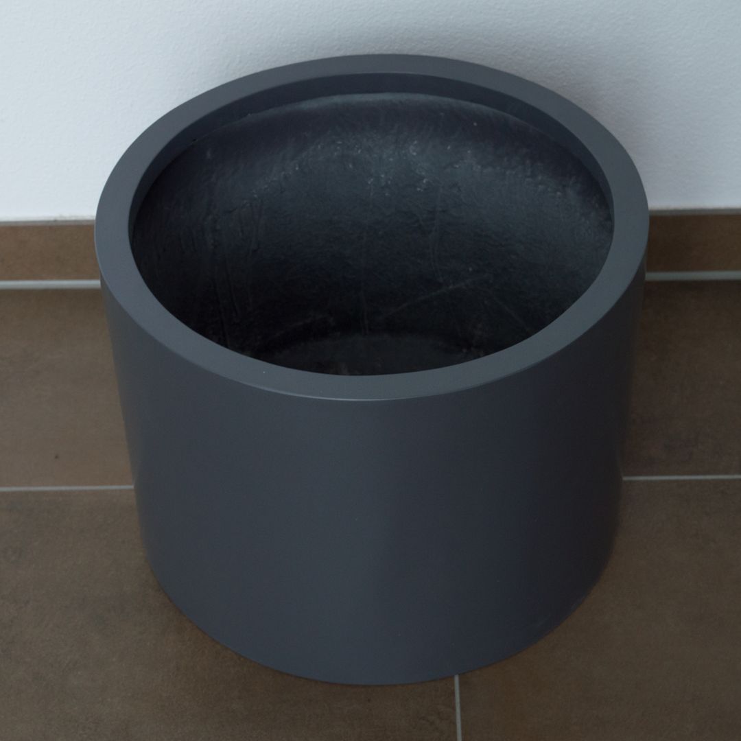 Zylindrischer Pflanzkübel aus Fiberglas in Anthrazit-Metallic von schräg oben mit Blick ins Innere auf Fliesenboden