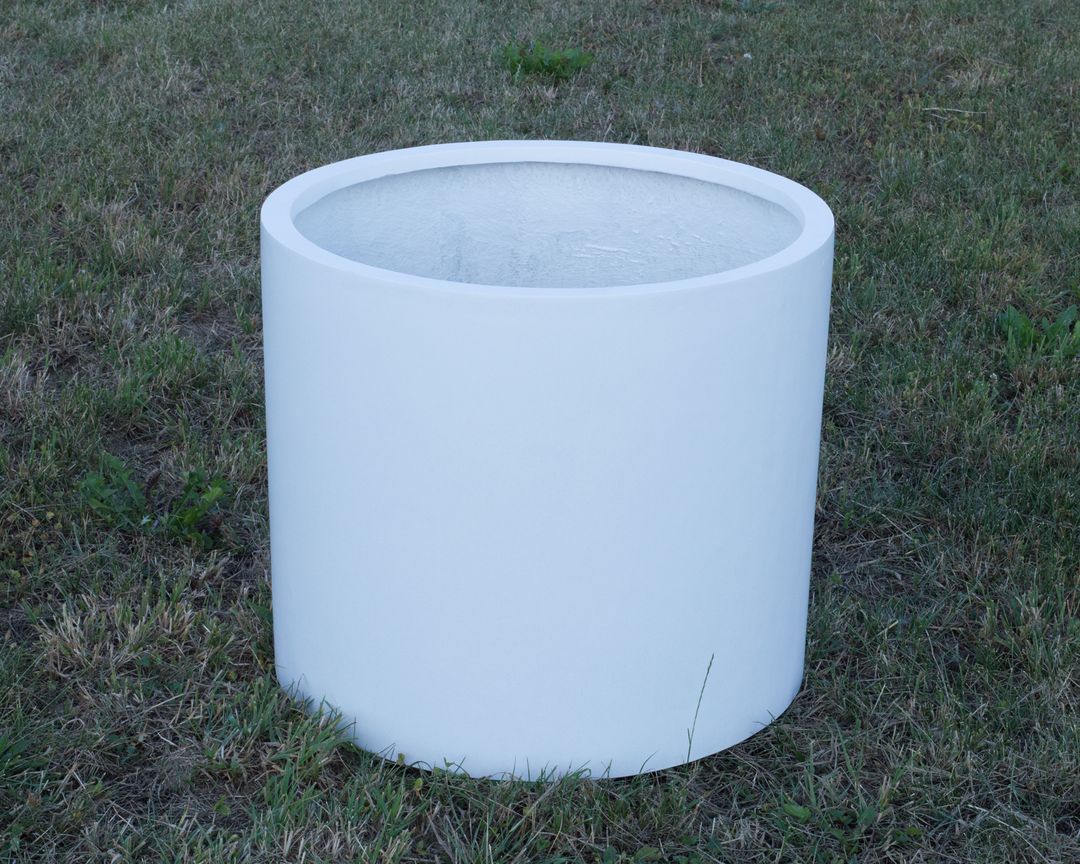 Zylindrischer Pflanzkübel aus Fiberglas in Perlmuttweiß, unbepflanzt auf einer Rasenfläche im Freien