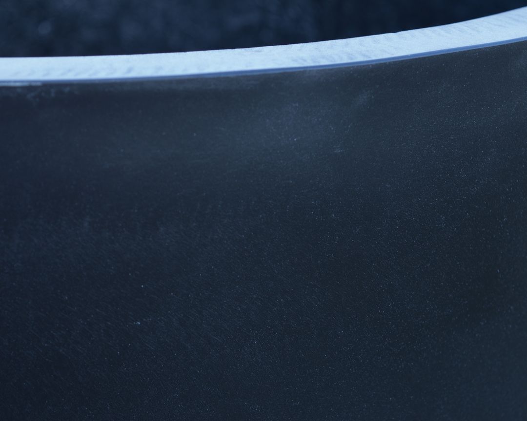 Nahaufnahme von Rand und Wandfläche eines schwarz-matten Pflanzkübels aus Fiberglas mit feiner Oberflächenstruktur