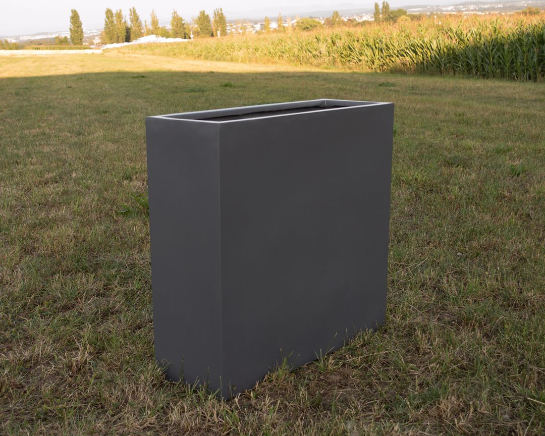 Rechteckiger Pflanzkübel aus Fiberglas in Anthrazit metallic ohne Bepflanzung auf einer Wiese vor einem Maisfeld