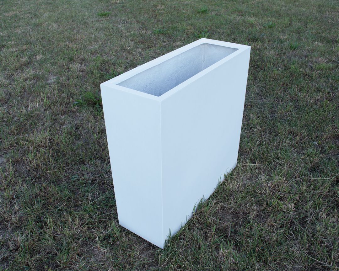 Rechteckiger, hoher und schmaler Pflanzkübel aus Fiberglas in Perlmuttweiß, unbepflanzt auf einer Rasenfläche